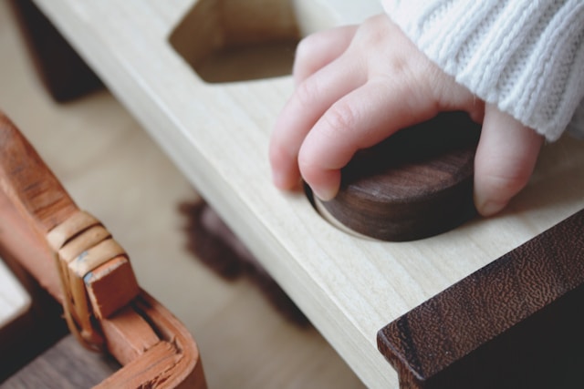 child's hand on wooden toy